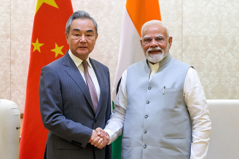 This handout photograph taken on August 19, 2025 and released by the Indian Press Information Bureau (PIB) shows India's Prime Minister Narendra Modi shaking hands with Beijing's Foreign Minister Wang Yi during a bilateral meeting in New Delhi on August 19, 2025. (Photo by Indian Press Information Bureau (PIB) / AFP) 