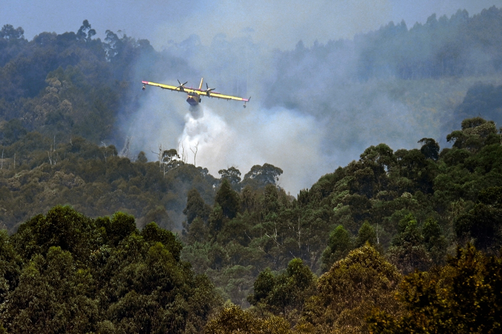 (Files) A firefighter airplane battles a wildfire near the village of Vilaboa, northwestern Spain on August 22, 2025. (Photo by Miguel Riopa / AFP)  
