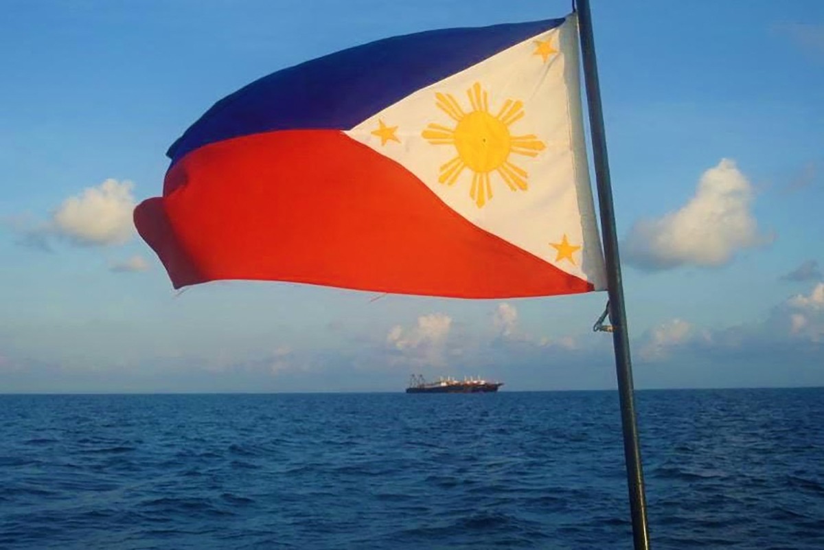 This handout photo taken April 14, 2021, and received from the Philippine Coast Guard (PCG) April 15, a Philippine flag is displayed aboard a coast guard rubber boat as they patrol past Chinese vessels at Whitsun Reef, in the Spratly Islands. Photo by Philippine coast Guard (PCG) / AFP.