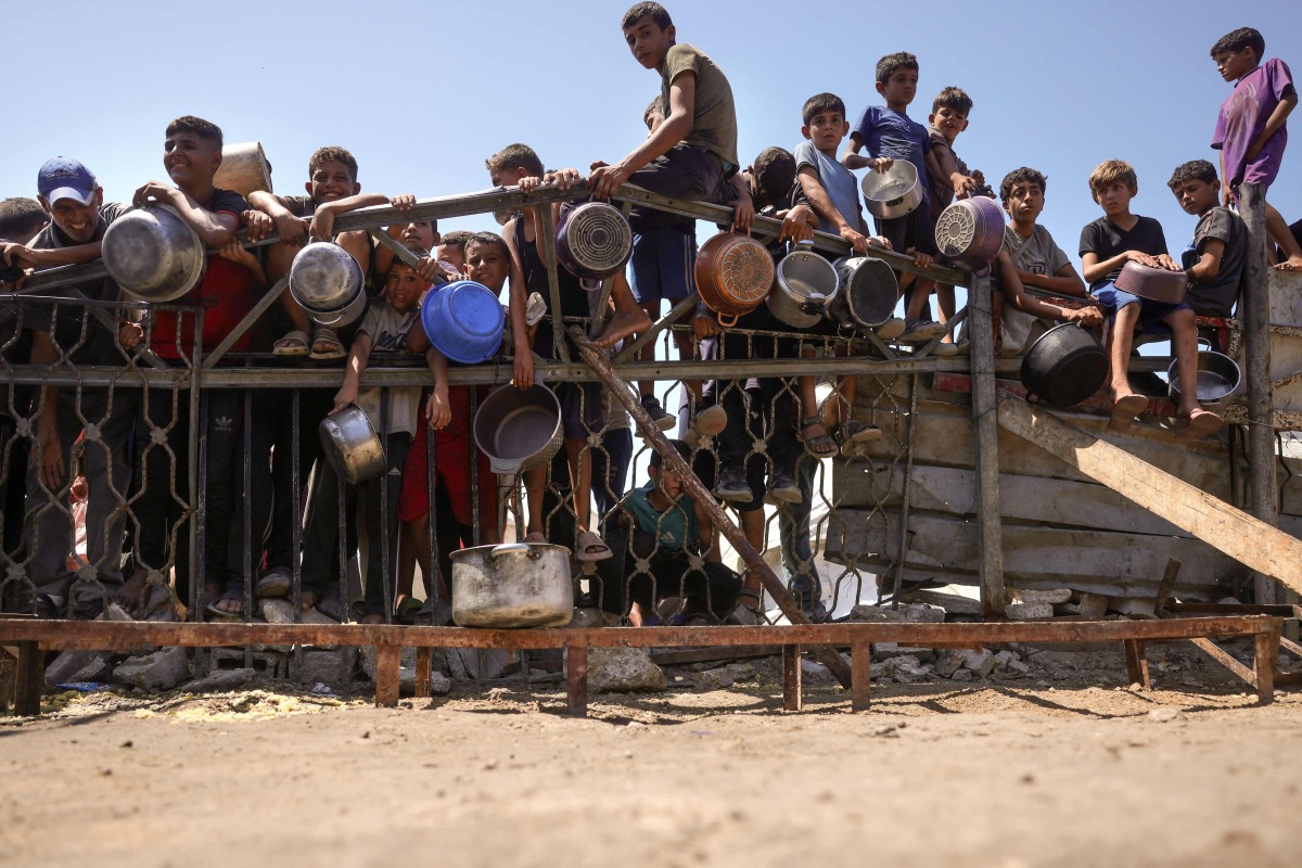 Children gather by a fence as they try to get rice from a charity kitchen providing food for free in the west of Gaza City, on August 28, 2025. Photo by BASHAR TALEB / AFP