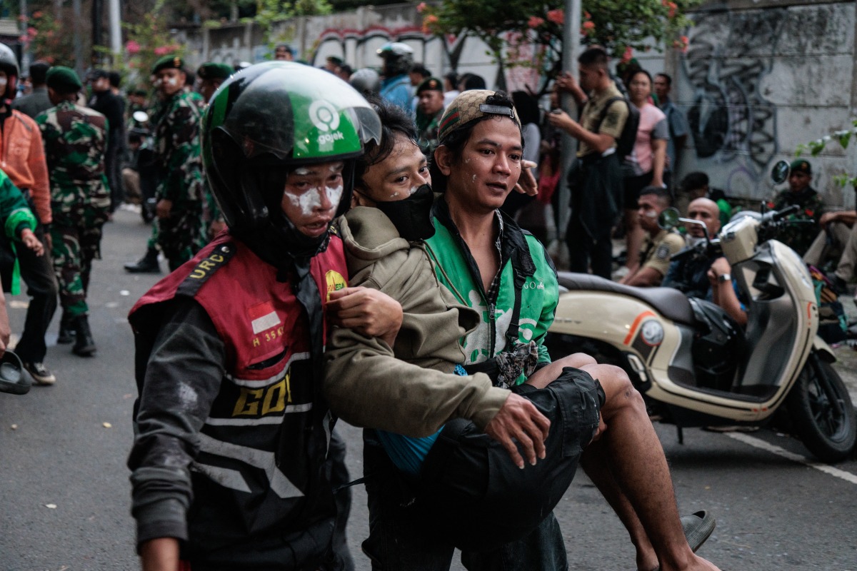 Protesters carry away a man who appears to be injured during a protest against the Mobile Brigade Corps, or 'Brimob', following the death of a motorcycle taxi driver the night before, in front of the Brimob headquarters in Jakarta on August 29, 2025. Photo by Aditya Aji / AFP.