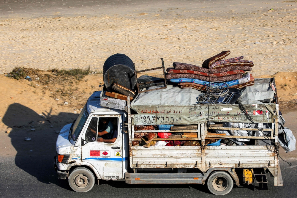 Displaced Palestinians fleeing in a truck with belongings along the coastal road through the Nuseirat camp in the central Gaza Strip on August 30, 2025. (Photo by Eyad Baba / AFP)