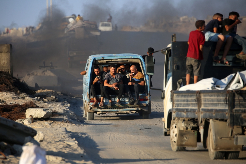 Palestinians fleeing south, ride vehicles with their belongings, on the coastal road near the Nuseirat refugee camp in the central Gaza Strip, on August 5, 2025. (Photo by Eyad Baba / AFP)