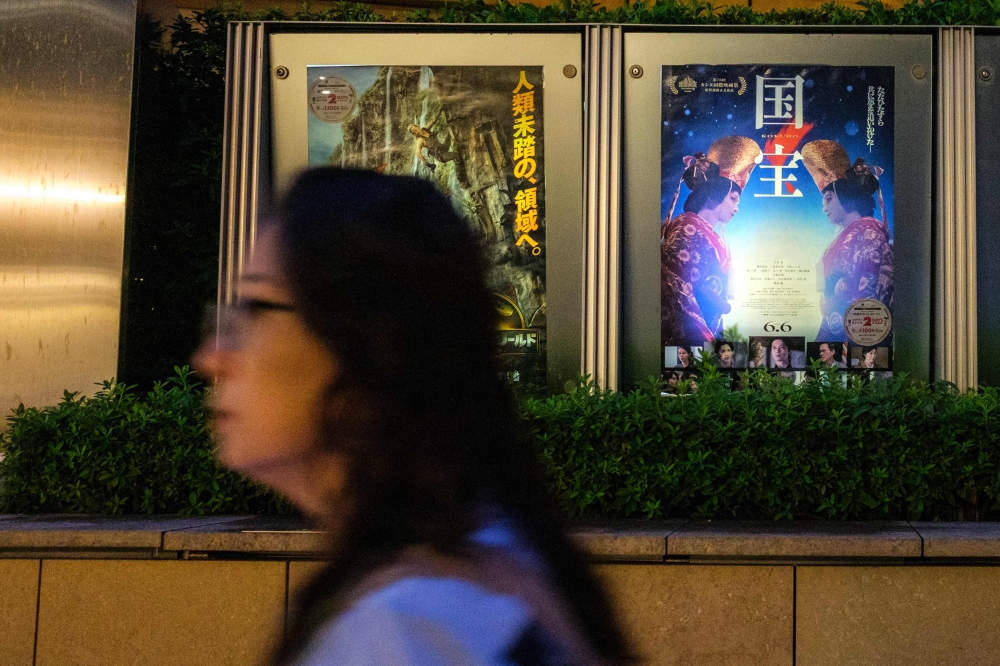 A woman walks past the poster of Japanese movie 