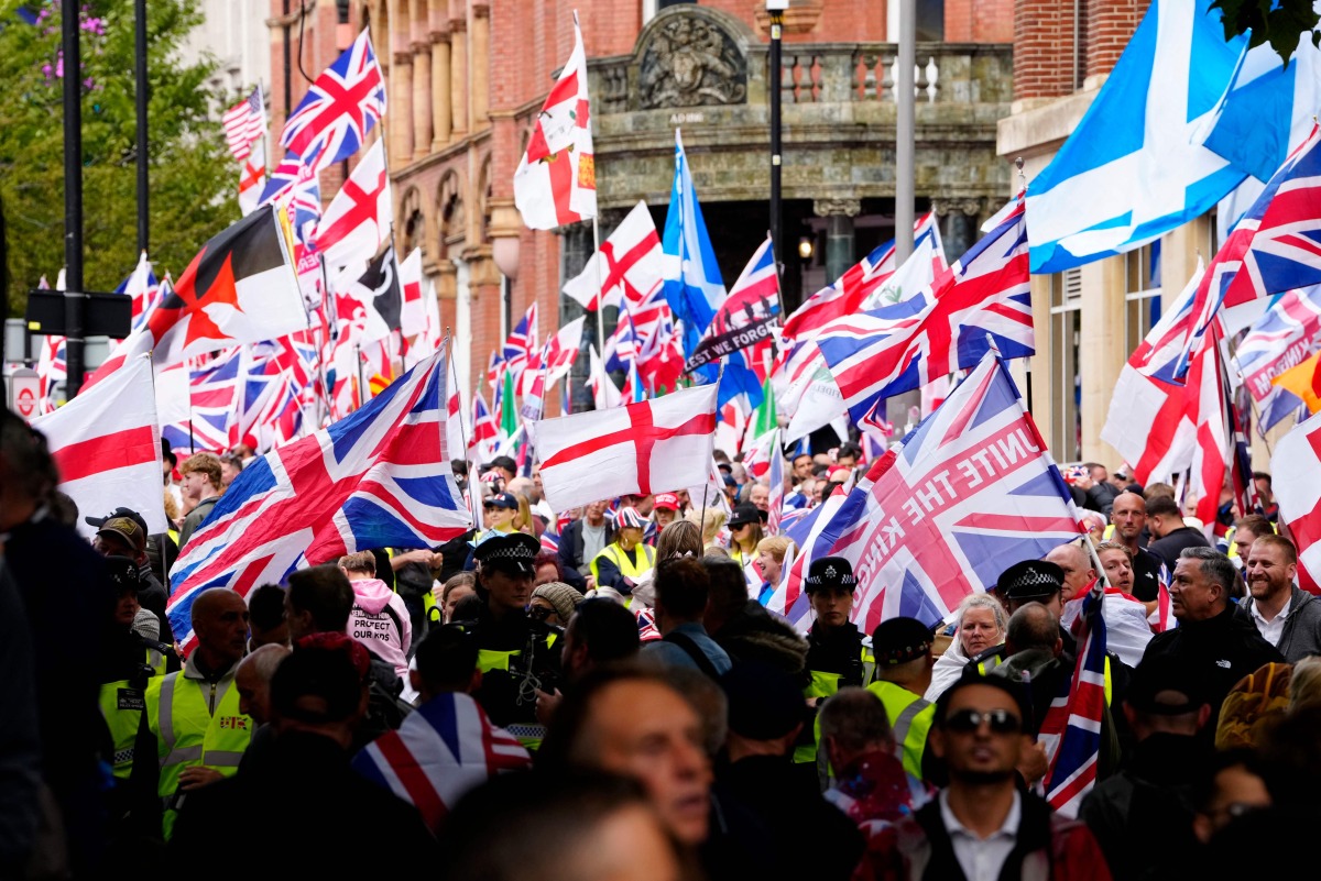 Supporters of British far-right activist Tommy Robinson whose real name is Stephen Yaxley-Lennon, walk through central London waving flags during a 'Free speech' march, on September 13, 2025. (Photo by CARLOS JASSO / AFP)