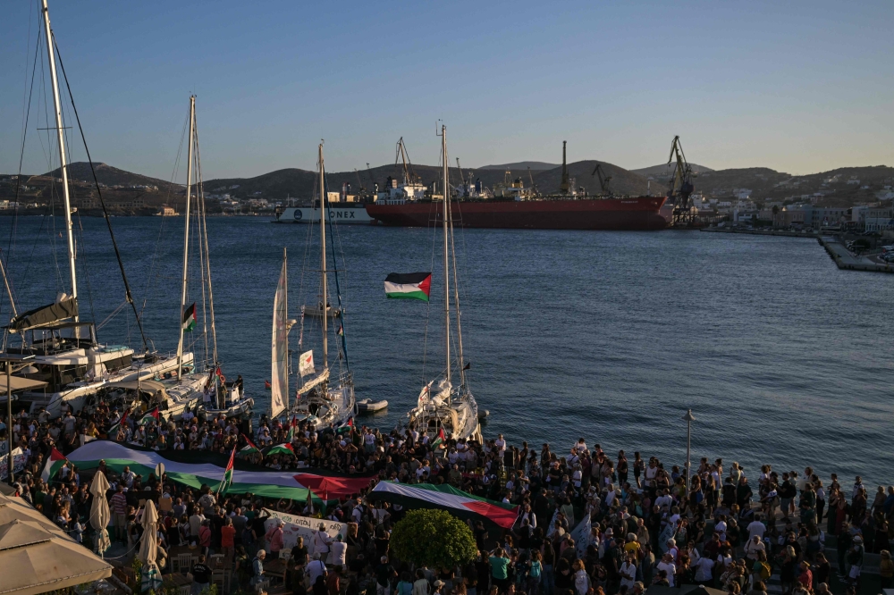 People gather at the port of Syros Island for the departure of two vessels, forming the Oxygen delegation to join the Global Sumud Flotilla, an international mission aiming to break the Israeli blockade of Gaza and to deliver humanitarian aid to Palestinians, on September 14, 2025. (Photo by Aris Messinis / AFP)