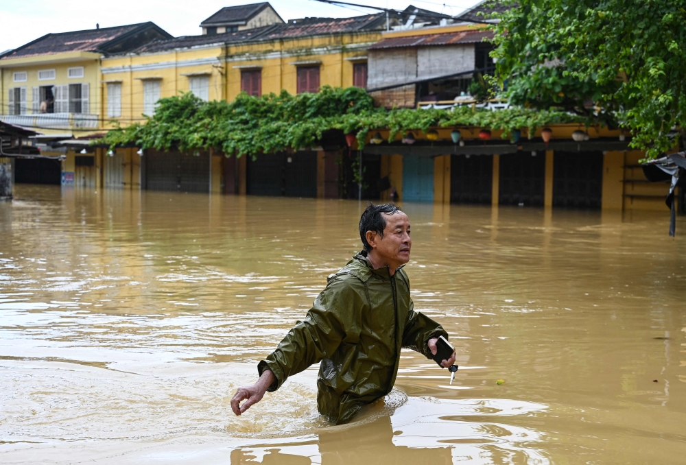 A man wades through a flooded street following heavy rains in Hoi An on October 30, 2025.  Photo by Nhac Nguyen / AFP