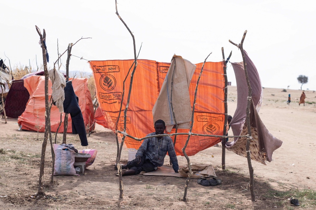 A displaced Sudanese man who fled El-Fasher after the city fell to the Rapid Support Forces (RSF), sits in a makeshift shelter in the Um Yanqur camp, located on the southwestern edge of Tawila, in war-torn Sudan's western Darfur region on November 3, 2025. (Photo by AFP)