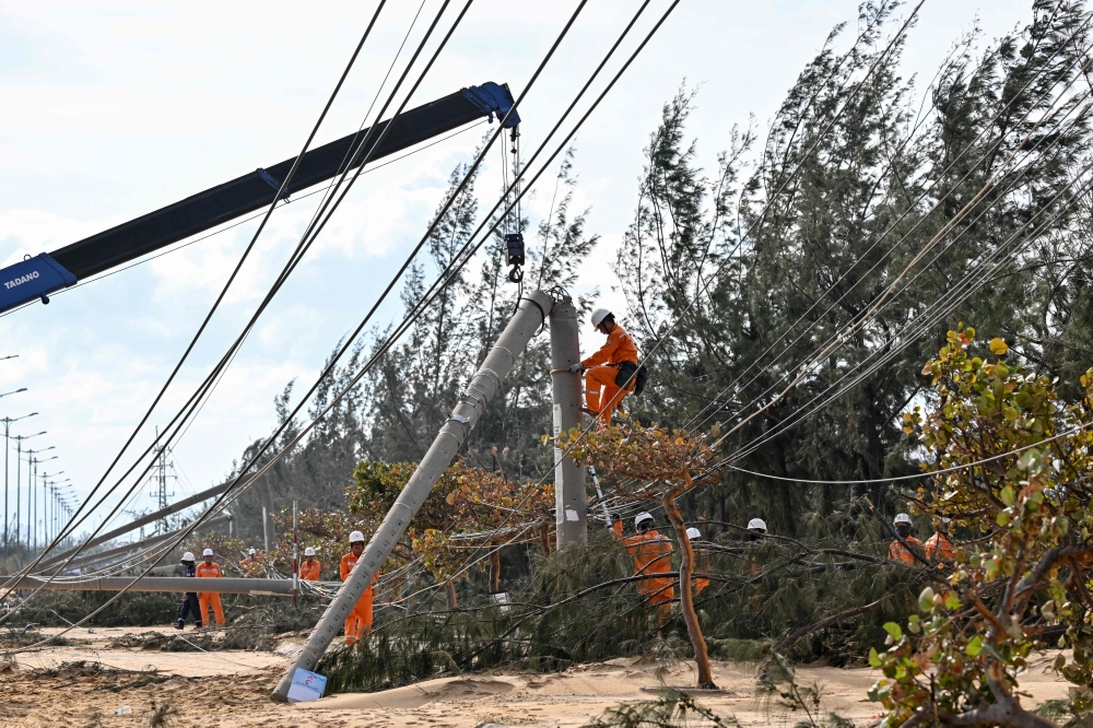 An electricity crew works on downed power lines to restore services in the aftermath of Typhoon Kalmaegi in Gia Lai province, central Vietnam on November 7, 2025. (Photo by Nhac Nguyen / AFP)