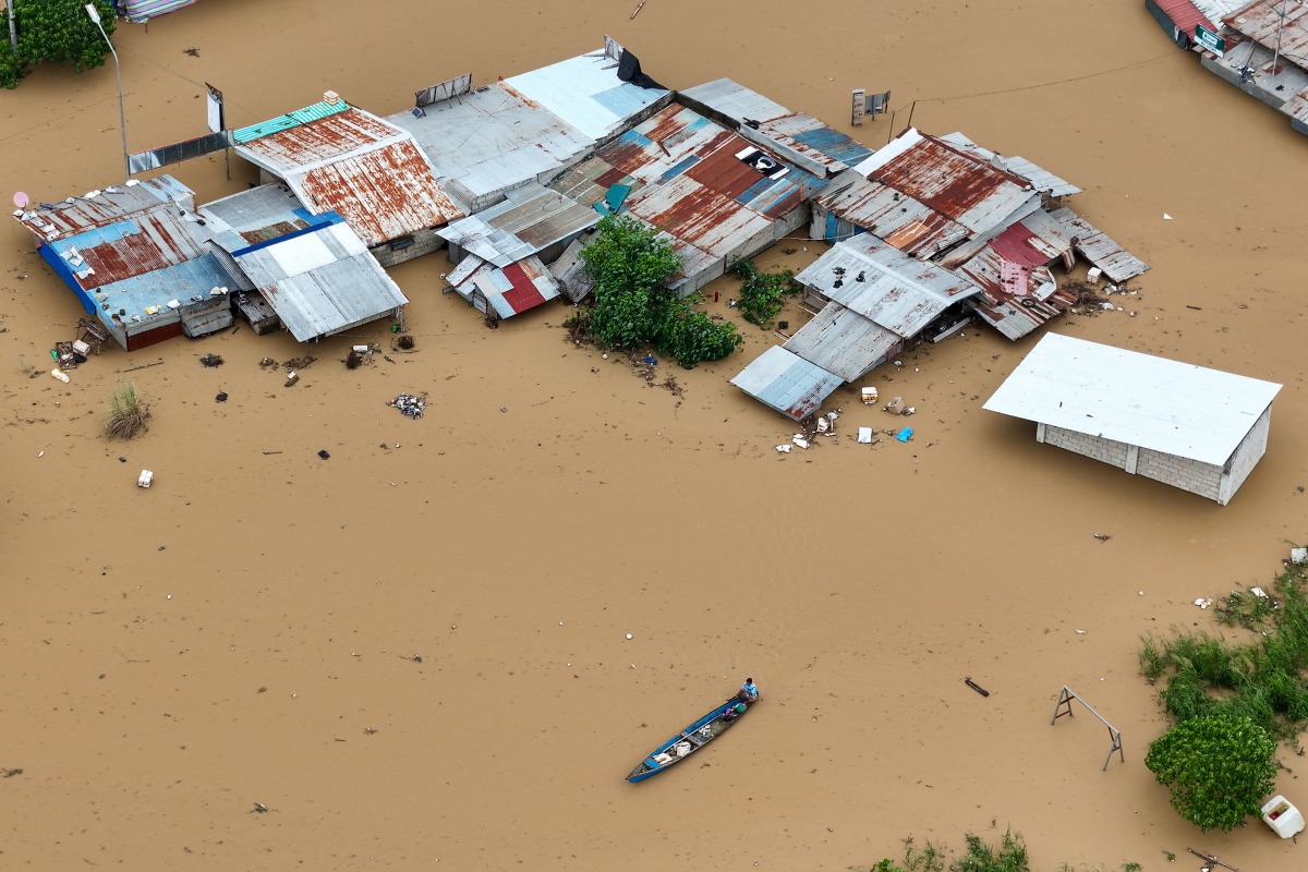 This aerial photo shows a resident paddles his boat in the flood waters past inundated houses in Tuguegarao City, Cagayan province, north of Manila on November 10, 2025, after a river overflowed following heavy rains brought about by Super Typhoon Fung-wong. Photo by JOHN DIMAIN / AFP