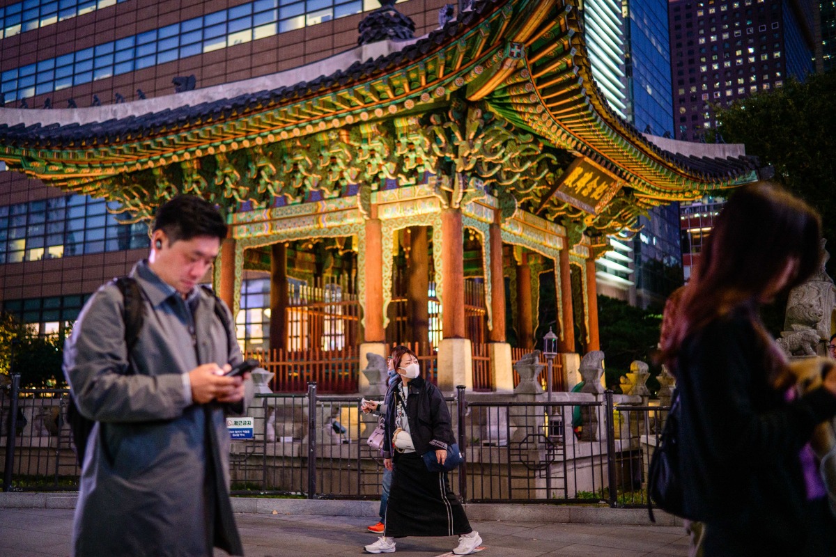 Pedestrians walk past the monument for the 40th anniversary of King Gojong's enthronement, built in 1902, in the Gwanghwamun district of Seoul on November 7, 2025. (Photo by ANTHONY WALLACE / AFP)
