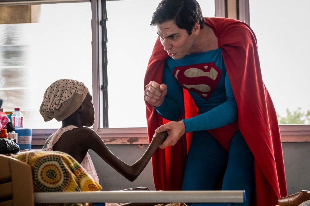 Leonardo Muylaert, known as the Brazilian Superman, greets a patient during a visit at the Korle Bu Teaching Hospital in Accra. (Photo by Claudia Lacave / AFP)