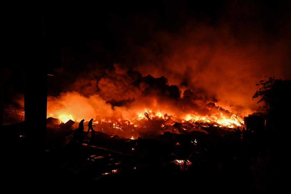 Firefighters work to extinguish a fire after an explosion in an industrial area of Ezeiza, Buenos Aires province, Argentina on November 15, 2025. Powerful explosions rocked an industrial area and ignited a fire south of Buenos Aires on the night of November 14, 2025, officials said, with at least 22 people sent to the hospital. (Photo by Luis Robayo / AFP