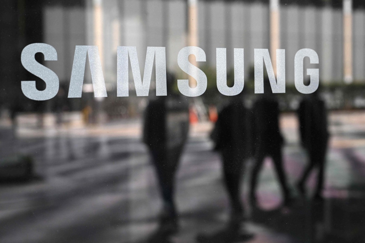 People walk past the Samsung logo displayed on a glass door at the company's Seocho building in Seoul on April 30, 2025. Photo by Jung Yeon-je / AFP