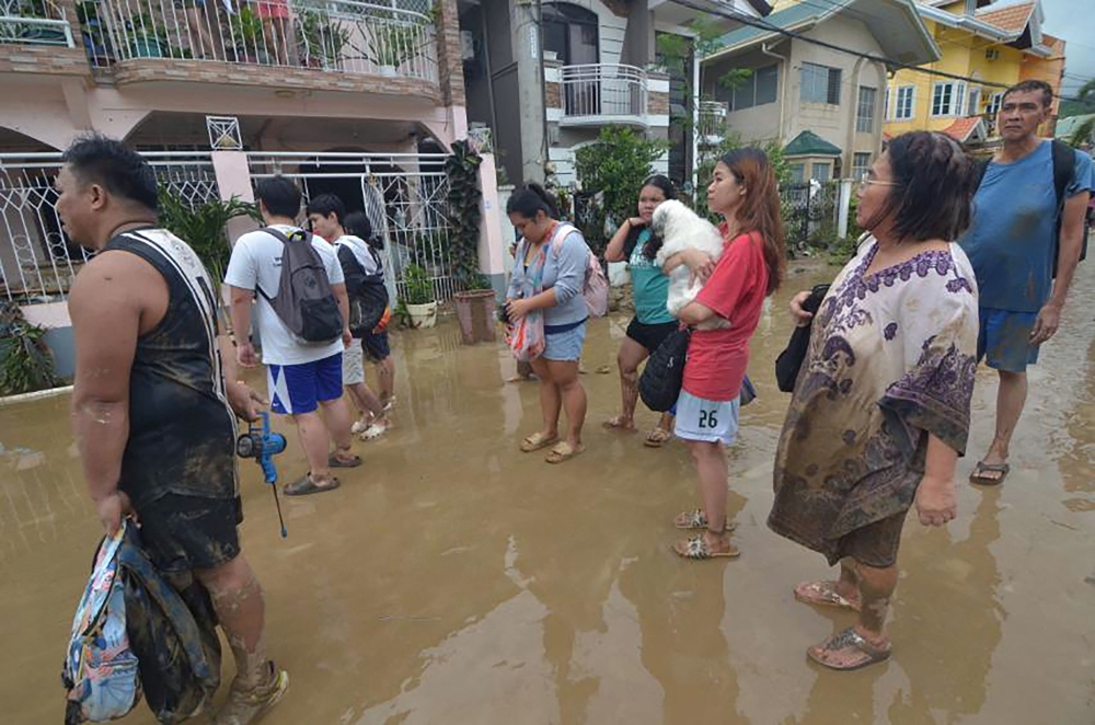 Residents stand in the mud as they wait to be evacuated from their flood-hit homes after Typhoon Kalmaegi hit Cebu City in the central Philippines on November 4. Photo by Alan Tangcawan / AFP