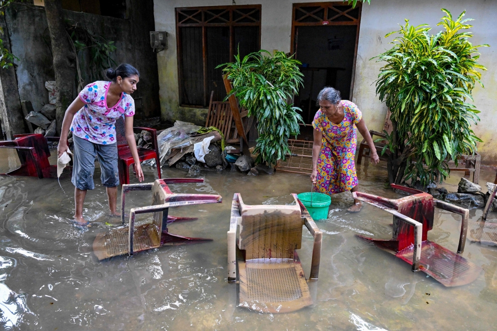 Residents salvage their belongings at an inundated house following flash floods in the aftermath of Cyclone Ditwah, in Wellampitiya on the outskirts of Colombo on December 3, 2025. (Photo by Ishara S. Kodikara / AFP)