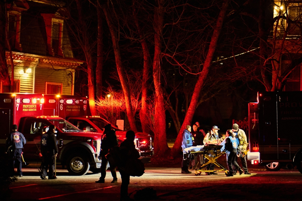 First responders with the Providence Fire Department maneuver an empty stretcher near the Barus & Holley building, home to the engineering and physics departments and the site of a mass shooting, at Brown University campus in Providence, Rhode Island, on December 13, 2025. The gunman killed two people and critically wounded eight others, authorities said, urging people in the area to remain in lockdown as the attacker was still at large. (Photo by Bing Guan / AFP)
