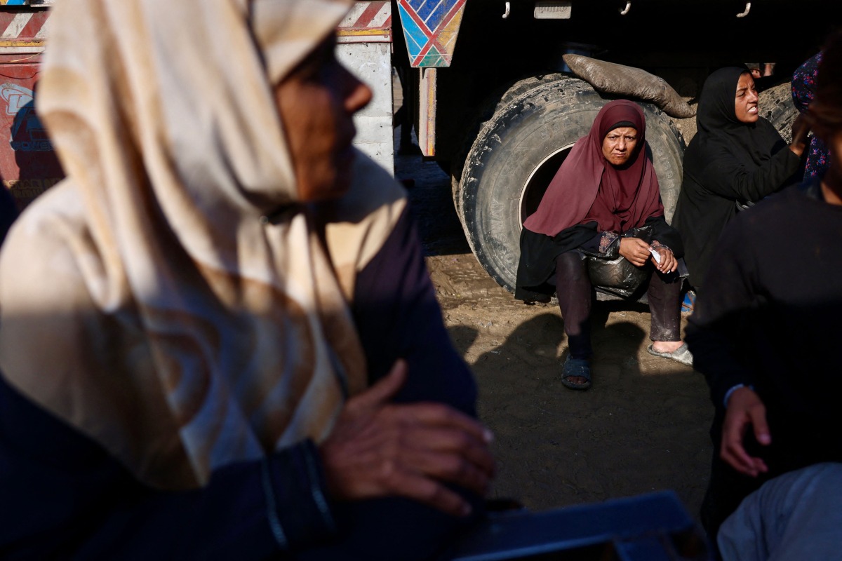 Displaced Palestinians wait to receive donated food portions at a charity kitchen in Khan Yunis in the southern Gaza Strip on December 17, 2025. (Photo by Bashar Taleb / AFP)
