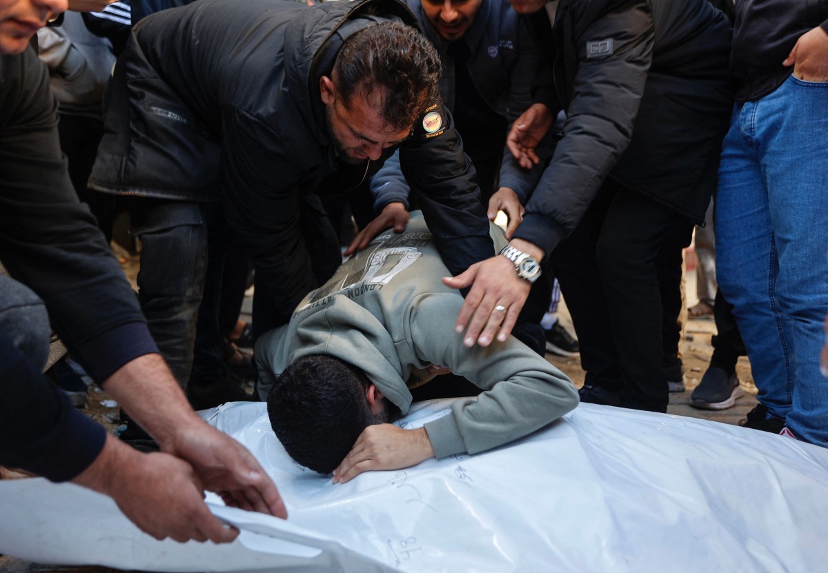 A relative mourns over the bodies of members of the Al-Nader family, who were reportedly killed the previous day in an Israeli shelling on a school-turned-shelter in the Tuffah neighbourhood of Gaza City, ahead of their funeral on December 20, 2025. (Photo by Omar AL-QATTAA / AFP)

