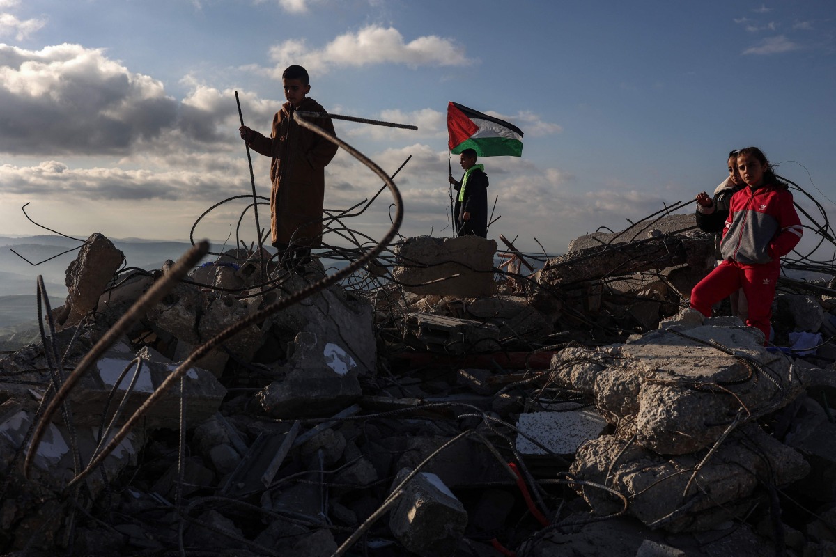 Children pose for photos taken by their parents on the rubble of a house demolished by Israeli authorities in the Palestinian village of Bizariya, in the Israeli-occupied West Bank, on December 24, 2025. (Photo by Zain JAAFAR / AFP)
