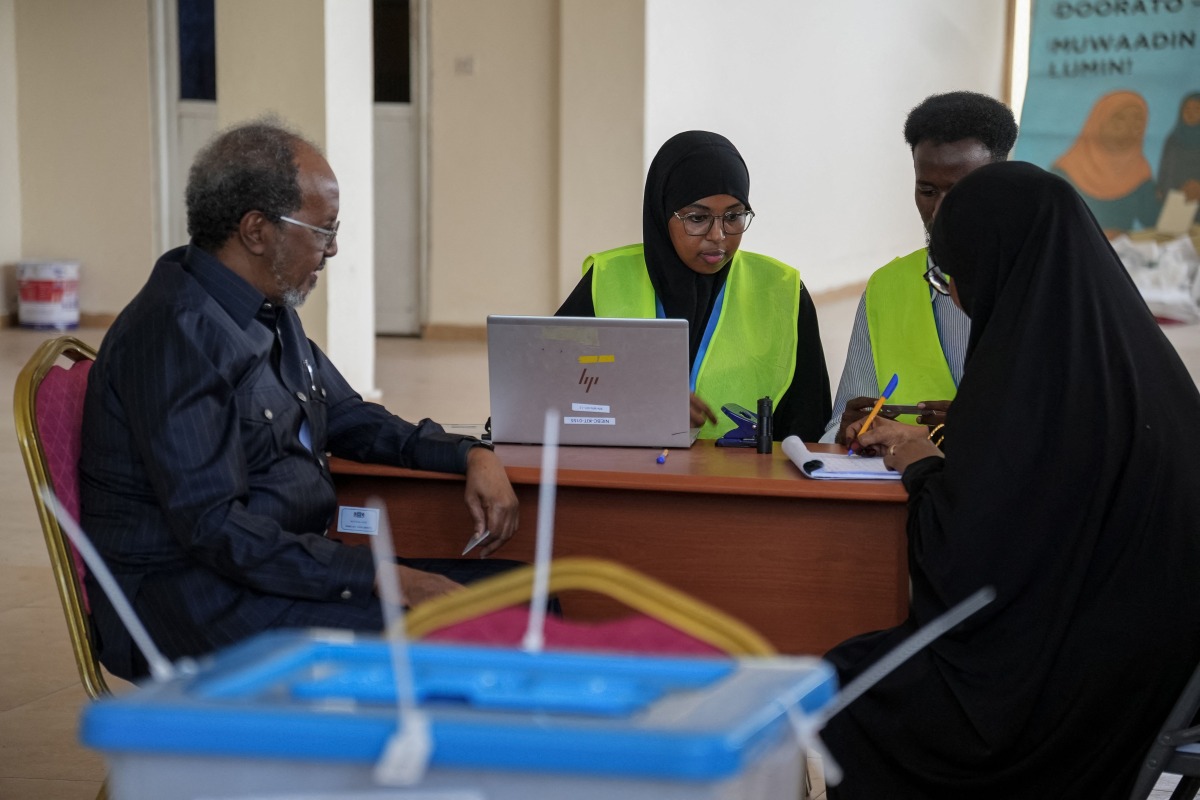 Electoral officials assist a voter at a polling station during local council elections in Mogadishu on December 25, 2025. (Photo by Hassan Ali ELMI / AFP)