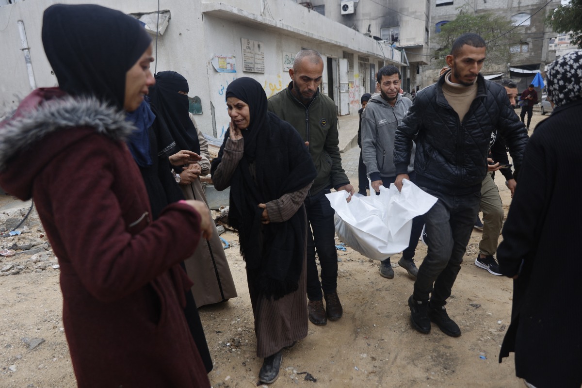 Relatives react as they carry a white body bag containing remains of a fire victim that started after the inhabitants ignited candles to light up inside their tents at a camp for displaced Palestinians in Gaza City on January 2, 2026. Photo by OMAR AL-QATTAA / AFP