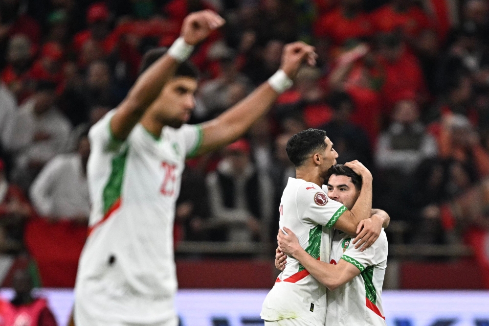 Morocco's forward #10 Brahim Diaz (R) celebrates scoring his team's first goal with Morocco's defender #02 Achraf Hakimi (2nd R) during the Africa Cup of Nations (CAN) quarter-final football match between Cameroon and Morocco at the Prince Moulay Abdallah stadium in Rabat on January 9, 2026. (Photo by Gabriel Bouys / AFP)