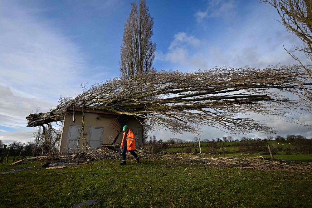 A worker secures the area around a fallen tree on a water borehole, following the passage of the storm Goretti, in Saint-Gabriel-Brecy, near Martragny, northwestern France. (Photo by Lou Benoist / AFP)