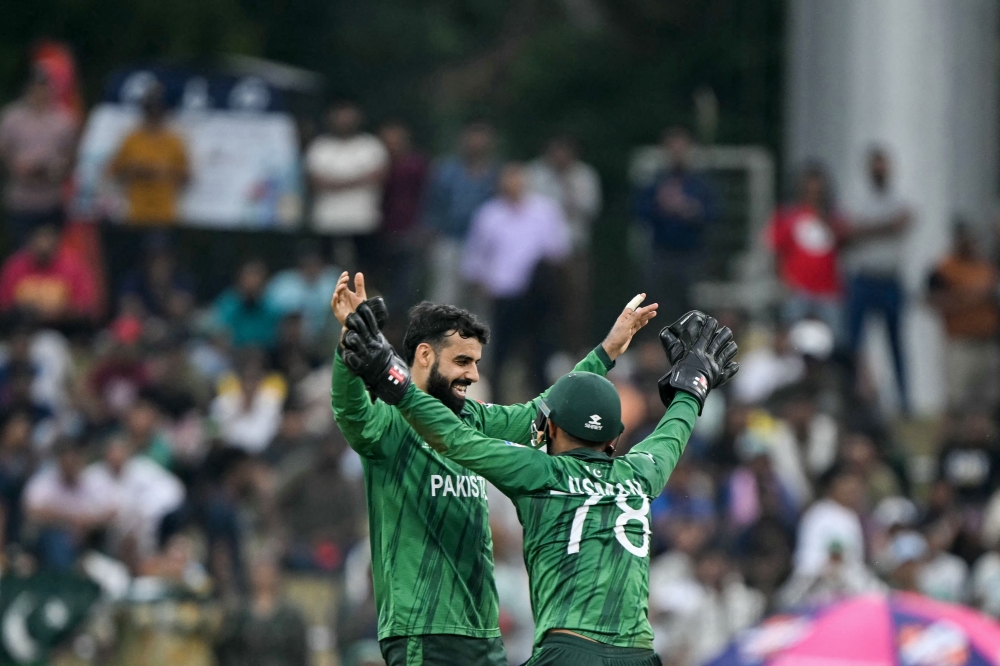 Pakistan's Shadab Khan (L) celebrates with wicketkeeper Usman Khan after taking the wicket of Namibia's Alexander Busing-Volschenk in Colombo on February 18, 2026. (Photo by Ishara S. Kodikara / AFP)