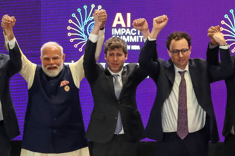 India's Prime Minister Narendra Modi (L) takes a group photo with AI company leaders including OpenAI CEO Sam Altman (C) and Anthropic CEO Dario Amodei (R) at the AI Impact Summit in New Delhi on February 19, 2026. (Photo by Ludovic Marin / AFP)
