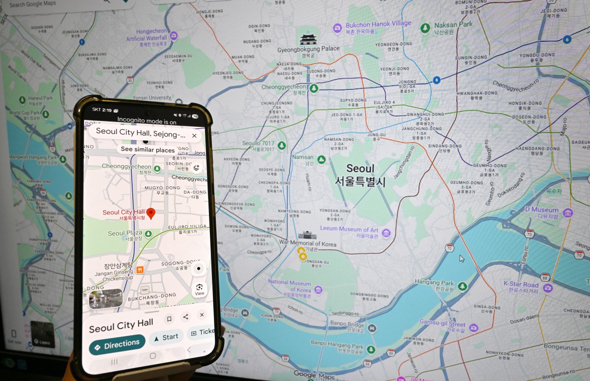 This photo illustration taken in Seoul on February 27, 2026 shows a Google Maps screen with a search for Seoul City Hall on a smartphone and a Google Maps webpage showing a map of Seoul. Photo by JUNG YEON-JE / AFP