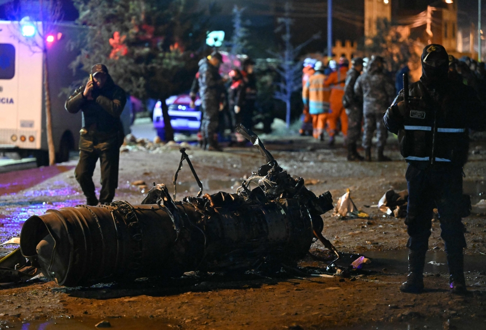 Military personnel stand next to pieces of a military plane that crashed in el Alto, near La Paz on February 27, 2026. At least 11 people were killed on February 27 when a Bolivian military cargo plane carrying banknotes crashed while landing near the capital city La Paz, prompting police to repel bystanders grabbing cash. (Photo by Aizar Raldea / AFP)