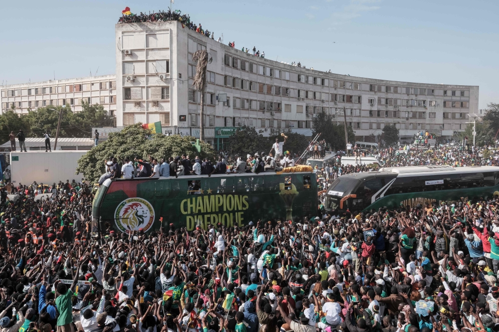 (Files) Supporters cheer as the Senegalese football players ride on a bus during a trophy parade in the streets of Dakar on January 20, 2026. (Photo by Guy Peterson / AFP)