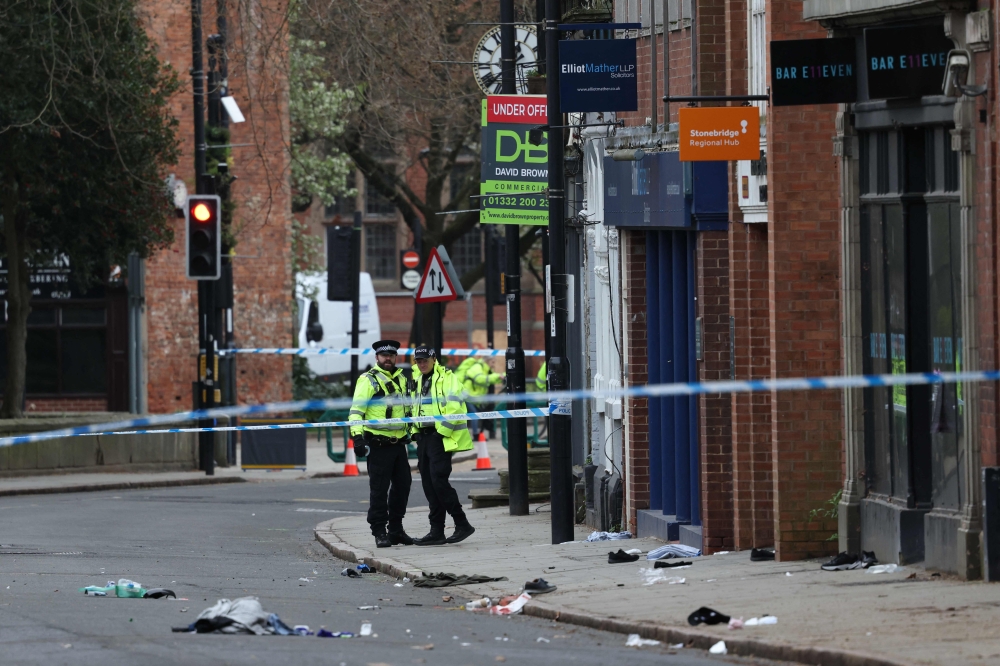 Police officers work near to a variety of personal items seen covering the road inside a cordon set up on Friar Gate in central Derby, central England on March 29, 2026. (Photo by Darren Staples / AFP)