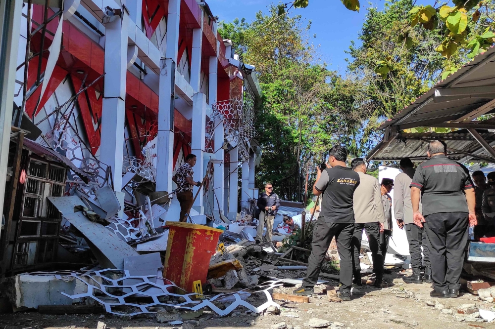 Police officers look at a building of the North Sumatra's National Sports Committee of Indonesia (KONI) damaged following a severe 7.4-magnitude offshore quake in Manado, North Sulawesi on April 2, 2026. (Photo by Tonny Rarung / AFP)