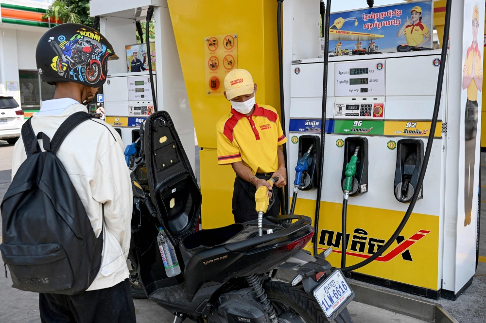 An employee pumps gasoline into the motorbike of a customer at a fuel station in Phnom Penh on April 1, 2026. (Photo by Tang Chhin Sothy / AFP)
