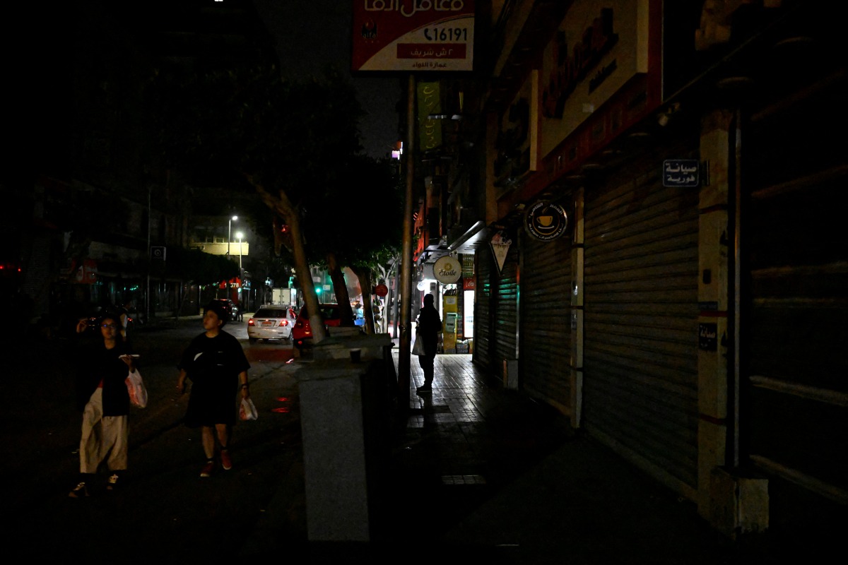 People walk past a closed cinema as shops close early under a government-ordered curfew aimed at reducing energy costs in downtown Cairo on April 2, 2026. Photo by KHALED DESOUKI / AFP