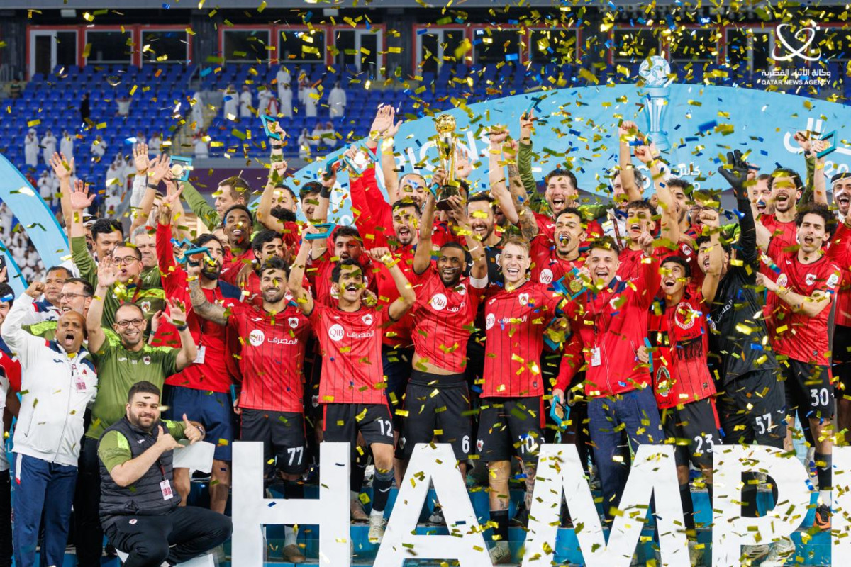 Al Rayyan players and officials celebrate with the trophy.