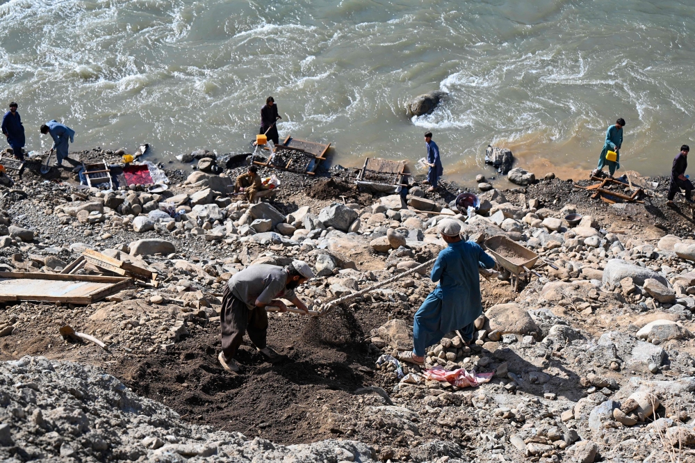 This photograph taken on April 13, 2026 shows Afghan men digging a mountainside along the Kunar riverbed before seiving stones in search of gold nuggets in the Song area of Ghaziabad district, Kunar province. (Photo by Wakil Kohsar / AFP)