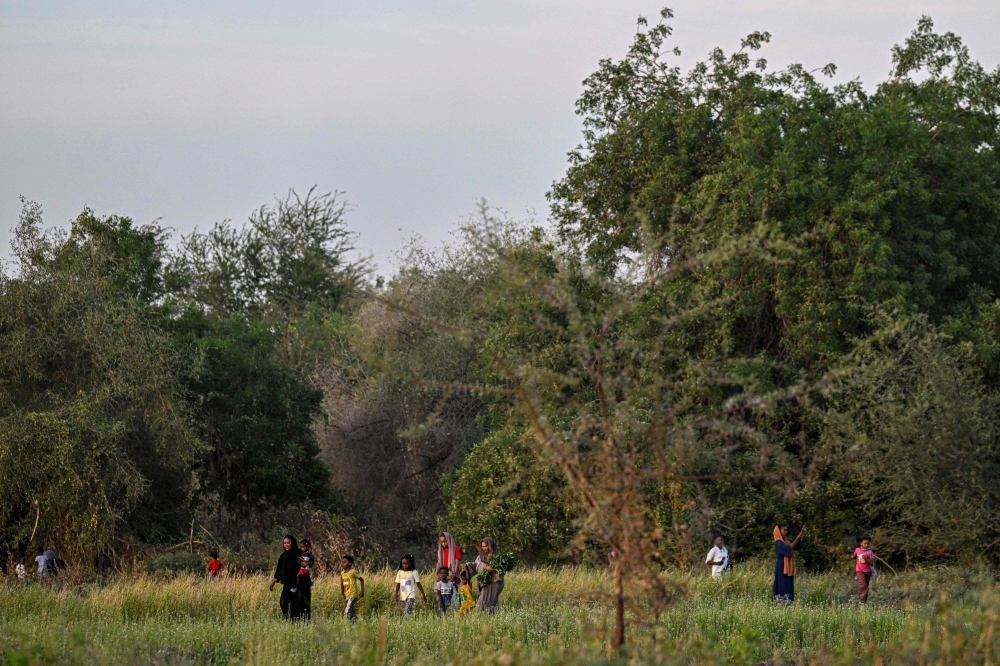 Sudanese local resident of Tuti Island walk across an agricultural field where the White Nile and Blue Nile merge to form the River Nile in the capital Khartoum on April 17, 2026. (Photo by Khaled Desouki / AFP)