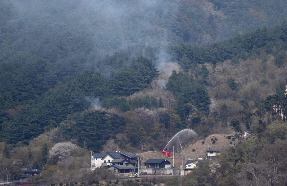 A fire engine sprays water on a hill side near homes in the town of Otsuchi, in Iwate Prefecture on April 25, 2026.(Photo by Andrew Caballero-Reynolds / AFP)