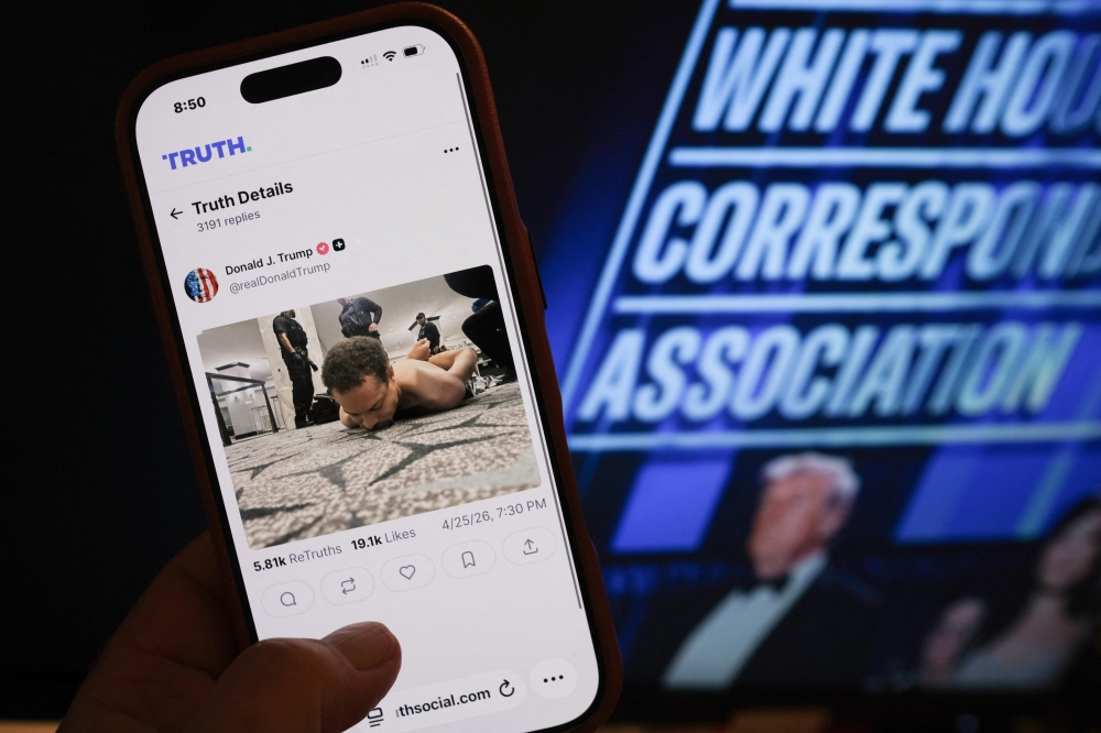 This illustration photo taken in Los Angeles shows a phone with a Truth Social post by US President Donald Trump displaying an image of the alleged suspect in a shooting incident at the White House Correspondents’ Dinner on the ground after being apprehended on April 25, 2026. (Photo by Chris Delmas / AFP)