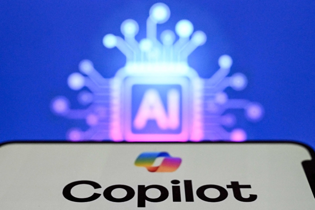 A photo taken on May 7, 2026 shows the letters AI for Artificial Intelligence on a laptop screen (top) next to the logo of the Microsoft's Copilot chatbot application on a smartphone screen in Frankfurt am Main, western Germany. (Photo by Kirill KUDRYAVTSEV / AFP)