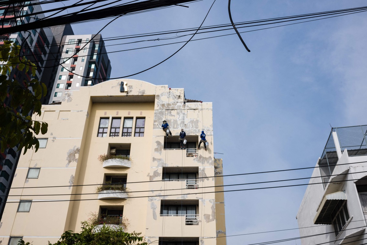 Workers repair the exterior of a building in Bangkok on May 8, 2026. (Photo by ANTHONY WALLACE / AFP)