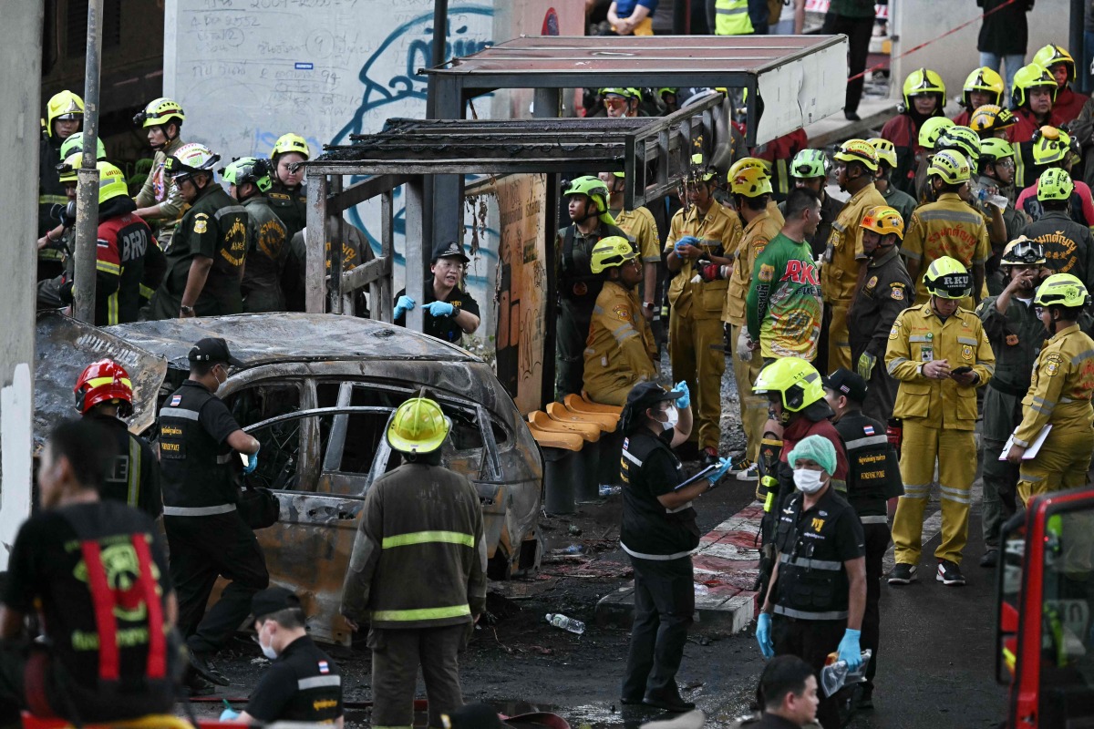 Forensic police officers, rescue workers and firefighters stand at the site of a train collision with a bus underneath Makkasan Airport Rail station in Bangkok on May 16, 2026. (Photo by Lillian SUWANRUMPHA / AFP)