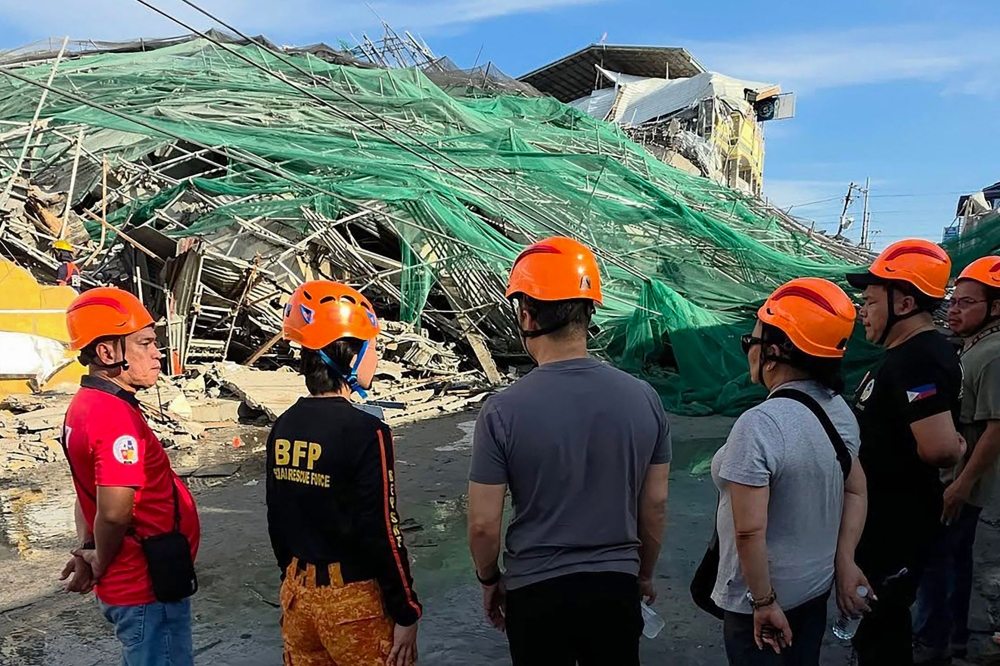 This handout photo taken and released on May 24, 2026 via the Facebook page of the Angeles City Public Information Office shows rescuers standing next to a collapsed building in Angeles City in Pampanga province. (Photo by Handout / Angeles City Public Information Office / AFP) 