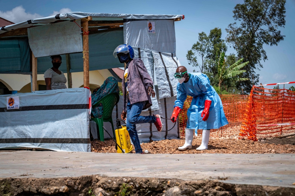 Dieudonné Sezabo, a health worker, decontaminates the clothing of a motorcycle taxi driver who transported a patient suspected of having Ebola to the Rwampara Hospital in Ituri, in the eastern Democratic Republic of the Congo. (Photo by Glody Murhabazi / AFP)