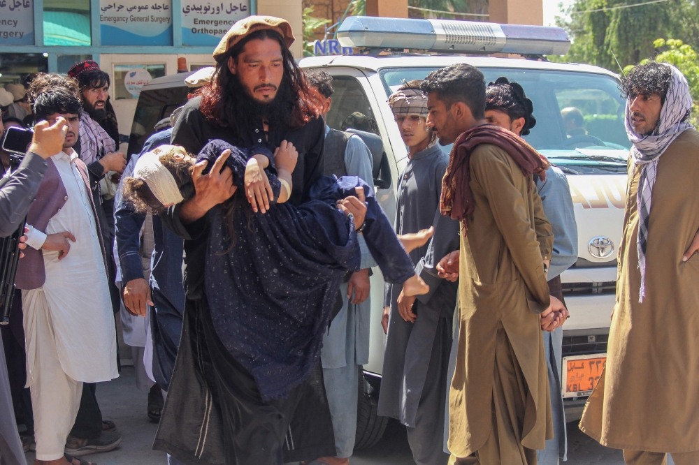 A man carries an injured girl to a hospital for treatment after a truck carrying Afghan families overturned in Jalalabad on May 30, 2026. (Photo by Aimal Zahir / AFP)