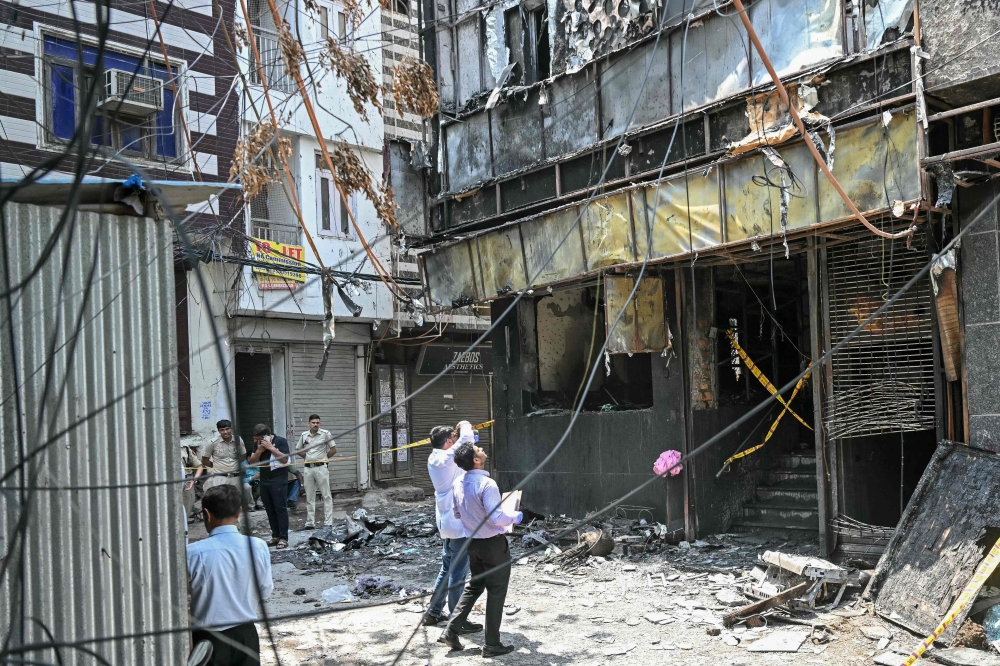 Forensics team members take photographs of the site following a fire that broke out at a hotel in New Delhi on June 3, 2026. (Photo by Arun Sankar / AFP)