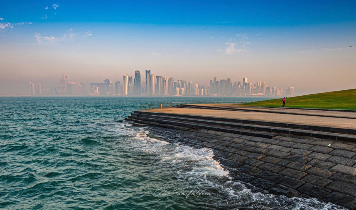 A runner is seen exercising along the Doha Corniche as waves splash along the shoreline e, with Doha's skyline standing prominently in the background. Pic: Qatarweather